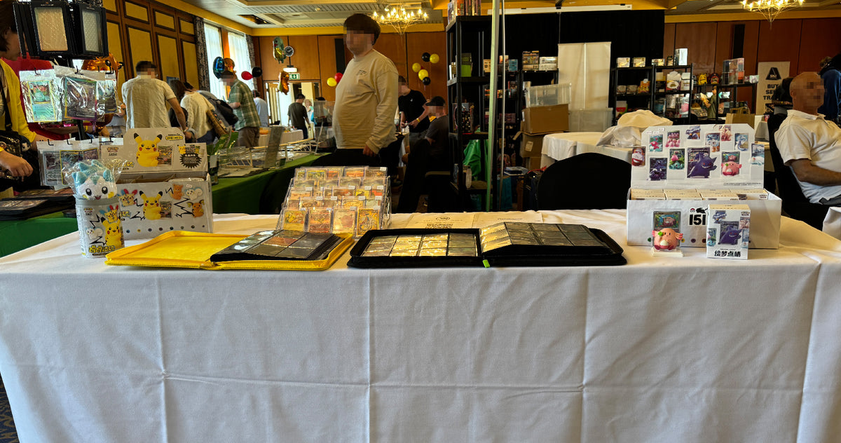 Collect Monsters table with binders and collectibles at a busy show